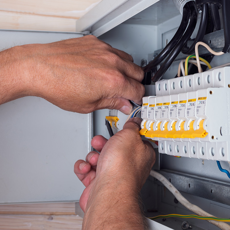 Electrician's hands skillfully connecting cables in an open distribution board