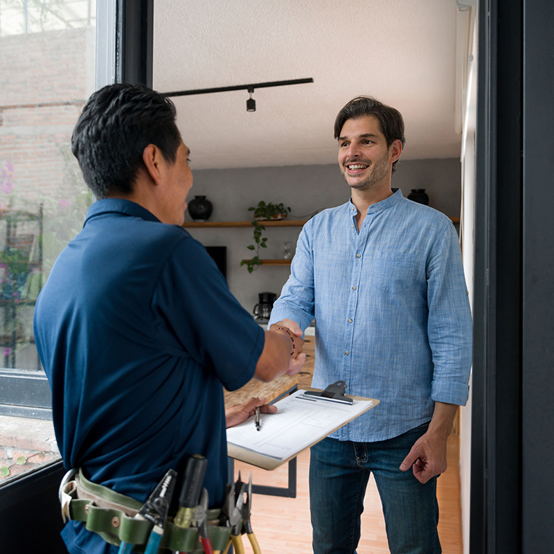 Electrician greeting a client with a handshake at the door of his house
