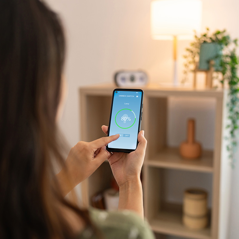Woman controlling light with a smart phone at home